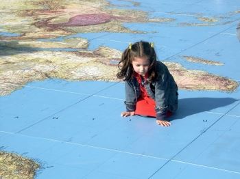 Little Girl Sitting on Map of the World